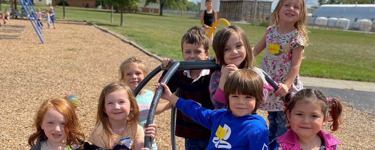 a group of boys and girls posing on the monkey bars at recess